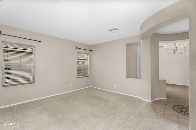 carpeted empty room featuring tile patterned floors, visible vents, baseboards, and a chandelier