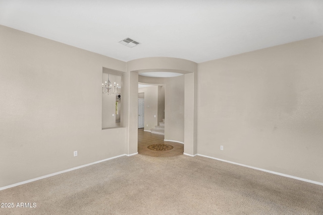 unfurnished room featuring visible vents, baseboards, carpet, and stairway