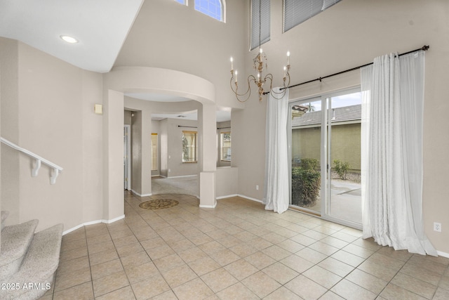 interior space featuring baseboards, stairs, light tile patterned floors, arched walkways, and a notable chandelier