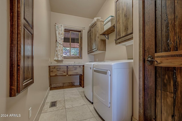 clothes washing area featuring cabinets, light tile patterned floors, and washing machine and clothes dryer