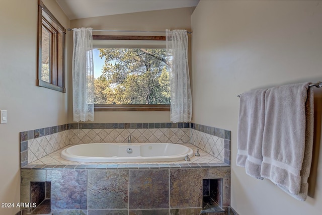 bathroom with tiled tub, plenty of natural light, and lofted ceiling