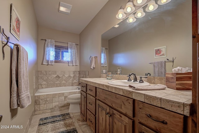 bathroom with tile patterned flooring, vanity, tiled bath, and toilet