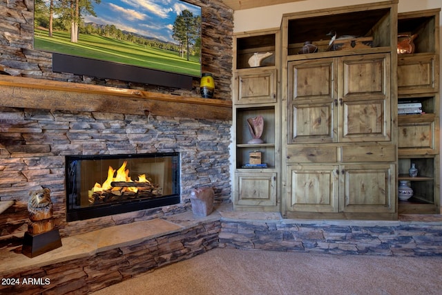 living room with built in shelves, an outdoor stone fireplace, and dark colored carpet