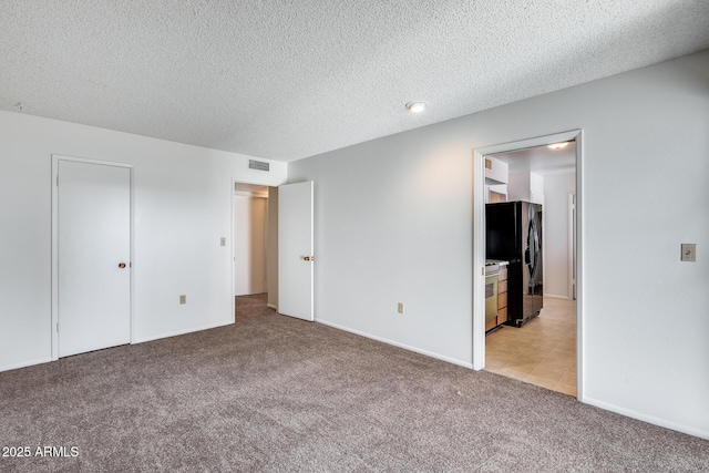 unfurnished bedroom with black refrigerator with ice dispenser, a textured ceiling, light carpet, and connected bathroom