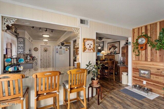 kitchen with white refrigerator, dark hardwood / wood-style floors, and wooden walls