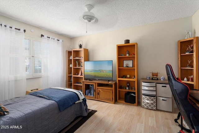 bedroom with ceiling fan, a textured ceiling, and light wood-type flooring