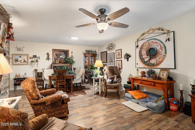 living room featuring ceiling fan, wood-type flooring, and a textured ceiling