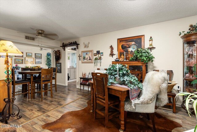 dining area with ceiling fan, a textured ceiling, and hardwood / wood-style flooring