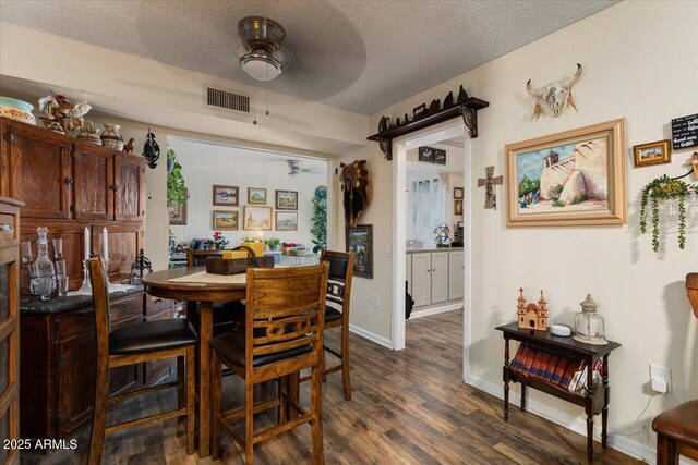 dining room with ceiling fan, dark wood-type flooring, and a textured ceiling