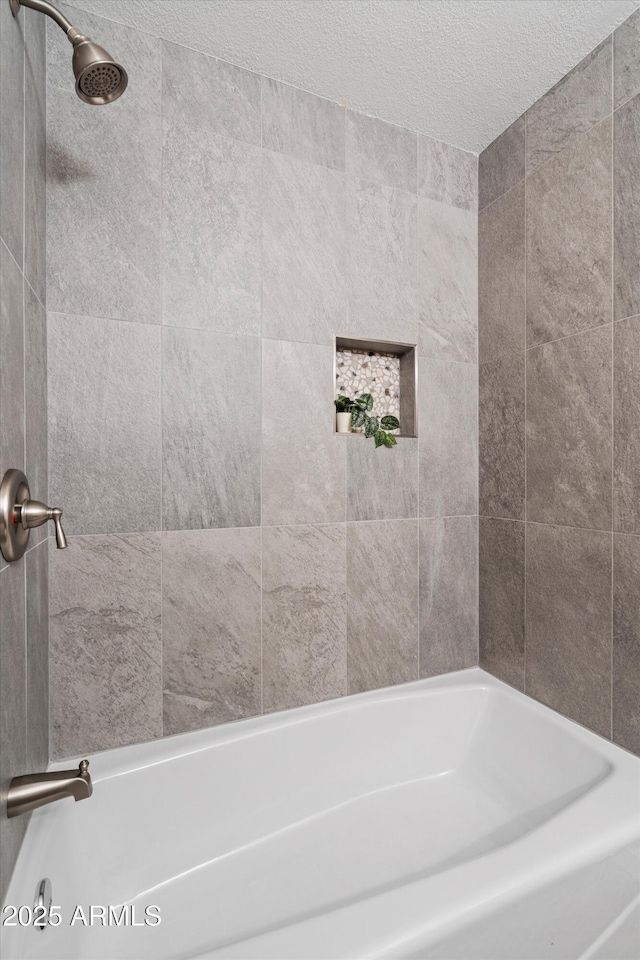 bathroom featuring tiled shower / bath combo and a textured ceiling