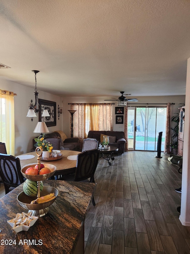 dining room with ceiling fan, dark wood-type flooring, and a textured ceiling