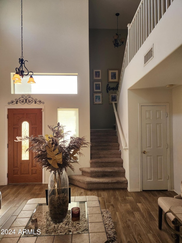 entrance foyer featuring a towering ceiling, a chandelier, wood-type flooring, and a wealth of natural light