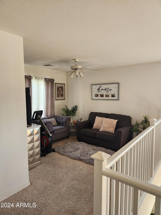 carpeted living room featuring ceiling fan and a textured ceiling