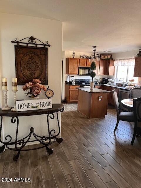 kitchen with dark hardwood / wood-style flooring, range with electric stovetop, a kitchen island, sink, and decorative light fixtures