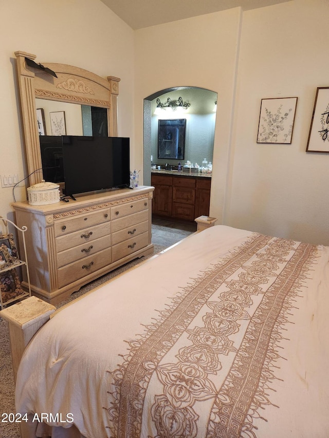 carpeted bedroom with connected bathroom and sink