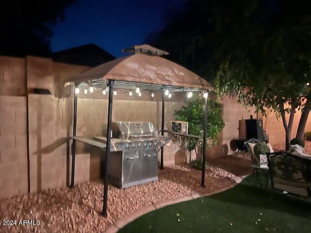 patio at twilight featuring a gazebo and a grill