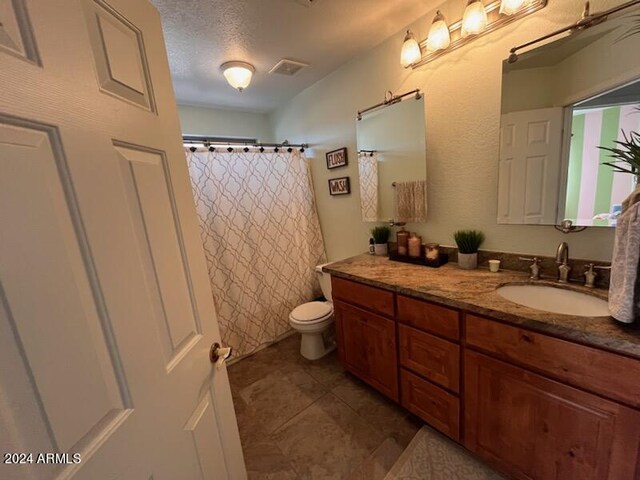 bathroom featuring a textured ceiling, toilet, vanity, and tile patterned flooring