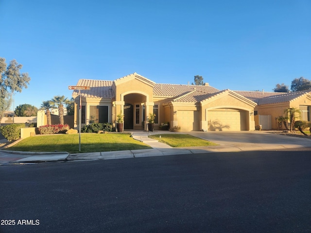 mediterranean / spanish-style home featuring a garage, a tiled roof, a front lawn, and stucco siding