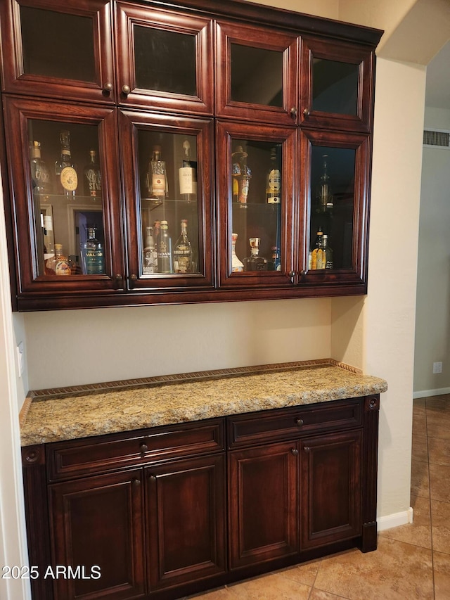 bar featuring light stone counters and light tile patterned flooring