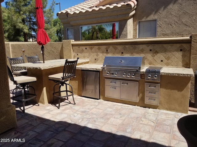 view of patio / terrace with a bar, a grill, and exterior kitchen