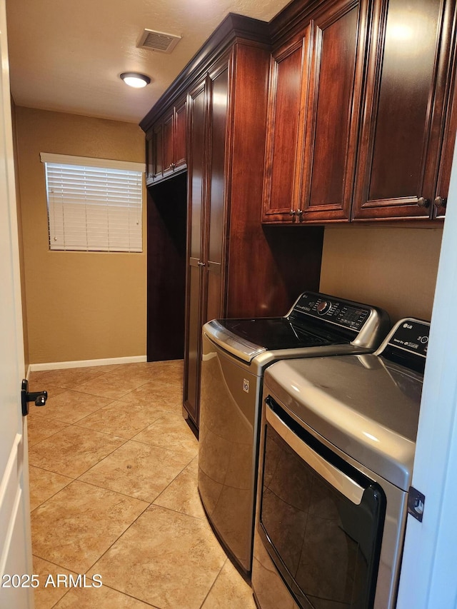 clothes washing area featuring cabinets, washer and dryer, and light tile patterned floors