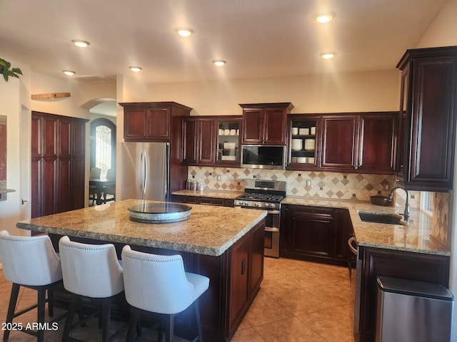 kitchen with tasteful backsplash, sink, a center island, light stone counters, and stainless steel appliances