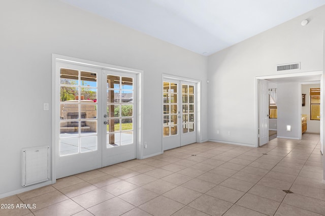 interior space with vaulted ceiling, french doors, visible vents, and baseboards