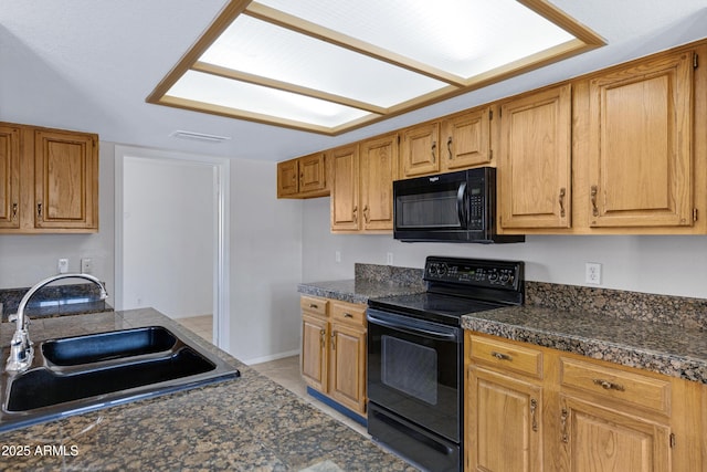 kitchen featuring light tile patterned floors, black appliances, brown cabinetry, and a sink