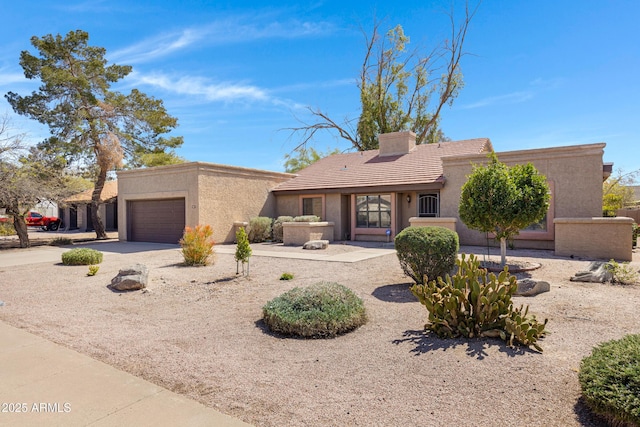 view of front of home featuring stucco siding, driveway, a chimney, and a garage