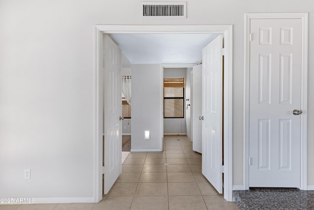 corridor featuring light tile patterned floors, baseboards, and visible vents