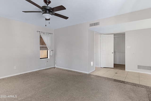 tiled empty room featuring carpet flooring, a ceiling fan, visible vents, and baseboards