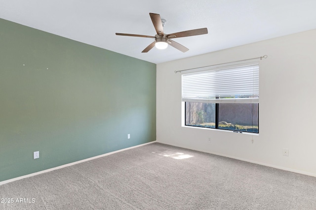 carpeted spare room with a ceiling fan and baseboards