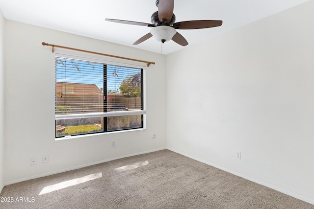 carpeted empty room with ceiling fan and baseboards