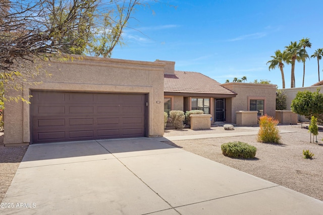 view of front of property featuring stucco siding, a tiled roof, concrete driveway, and a garage