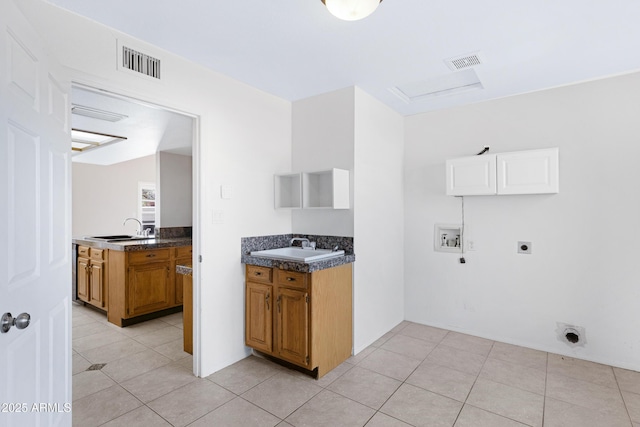 kitchen with a sink, dark countertops, visible vents, and brown cabinets