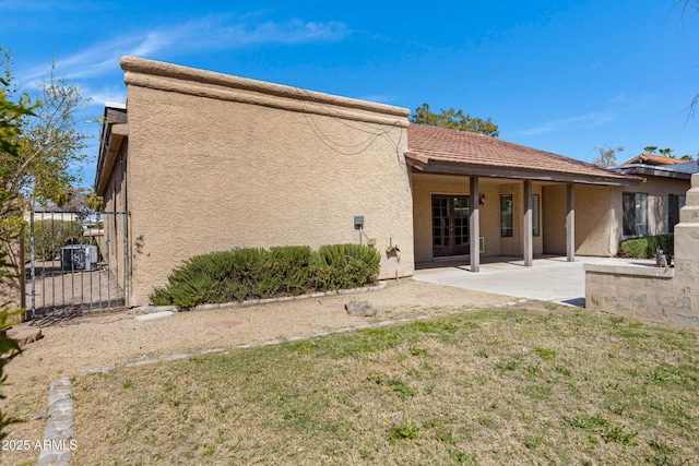 rear view of house with a patio area, stucco siding, a yard, and fence