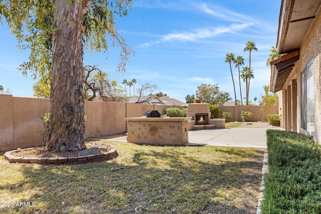 view of yard with a fenced backyard, a patio area, and a lit fireplace