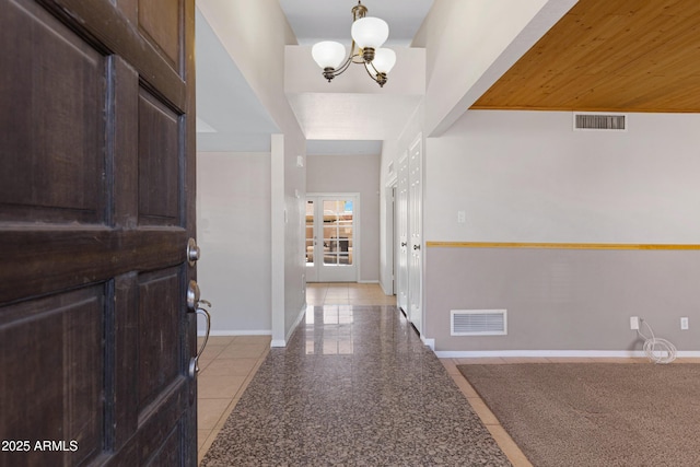 hall featuring granite finish floor, visible vents, an inviting chandelier, and baseboards