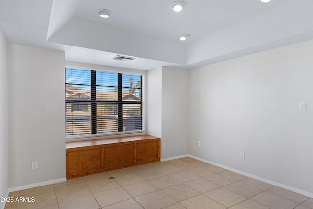 unfurnished room with a raised ceiling, light tile patterned flooring, visible vents, and baseboards