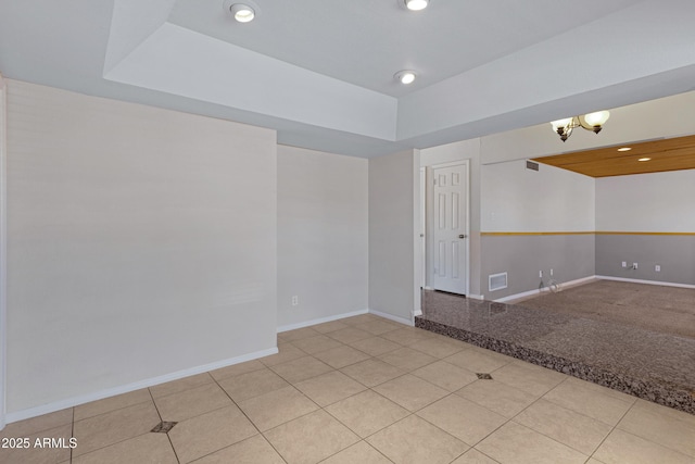 tiled spare room featuring recessed lighting, baseboards, and a raised ceiling