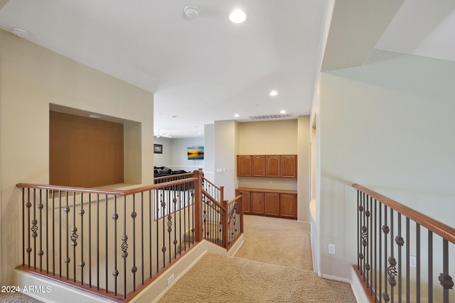hall featuring visible vents, light carpet, recessed lighting, and an upstairs landing