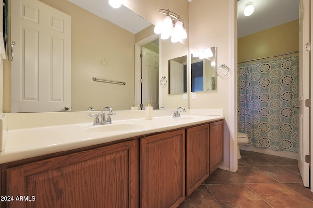 bathroom featuring double vanity, a sink, tile patterned floors, and toilet