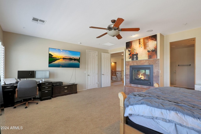 carpeted bedroom featuring a ceiling fan, baseboards, visible vents, and a tiled fireplace