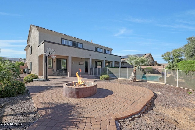 back of property with fence, a patio, stucco siding, a fenced in pool, and an outdoor fire pit