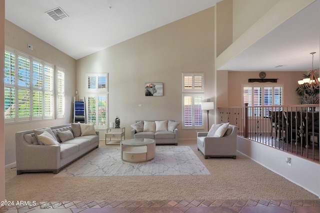 living room featuring visible vents, baseboards, high vaulted ceiling, a chandelier, and carpet