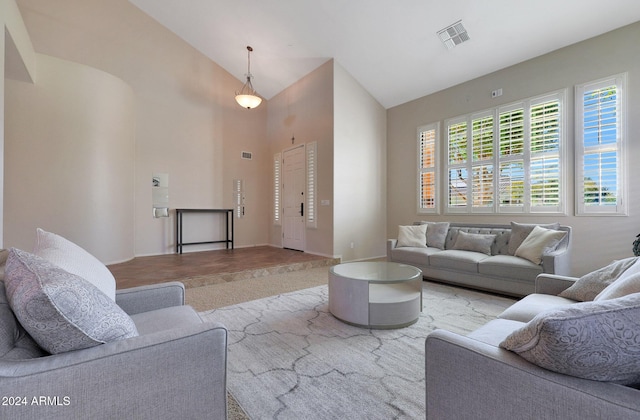 living room with high vaulted ceiling, visible vents, and baseboards
