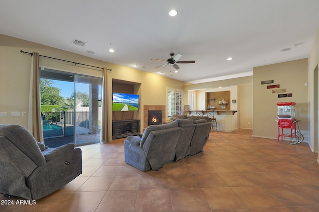 living room with a tiled fireplace, ceiling fan, and light tile patterned flooring