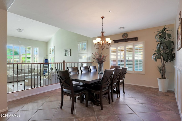 tiled dining area with visible vents, baseboards, lofted ceiling, and an inviting chandelier