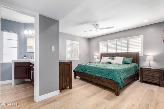 bedroom featuring ensuite bathroom, ceiling fan, and light wood-type flooring