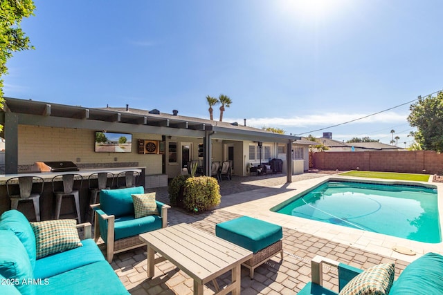 view of pool featuring a bar, a grill, exterior kitchen, an outdoor living space, and a patio area